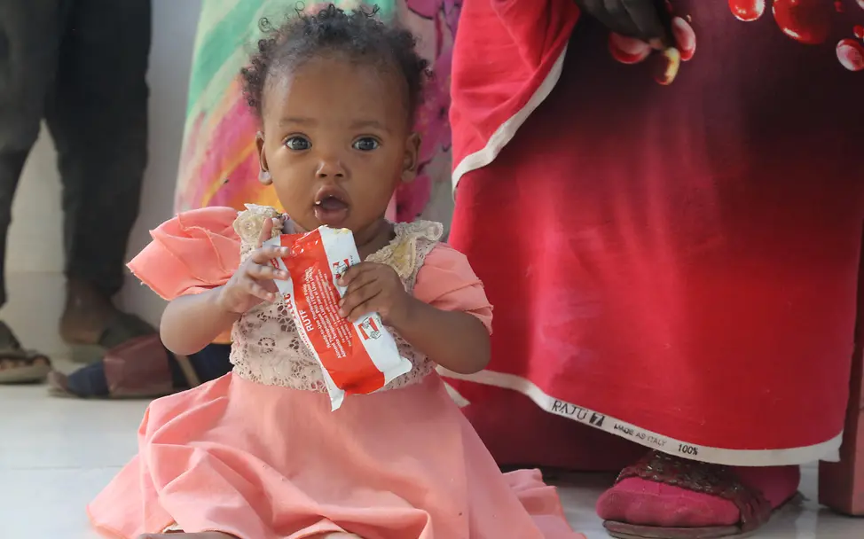 Mangelernährung im Sudan | © UNICEF/UNI593617/Hasouna Ein Kleinkind wird mit reichhaltiger Erdnusspaste versorgt