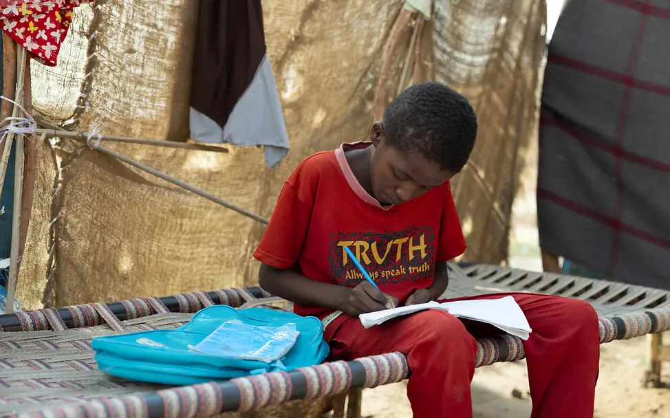 Der Bildungsweg wird durch eine Flucht oft unterbrochen | UNICEF/UNI889553/Dawod Ein Junge lernt auf einem Feldbett