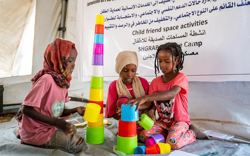 Kinder spielen in einem kinderfreundlichen Ort | UNICEF/UNI837611/Rajab Drei Mädchen spielen mit Bauklötzen