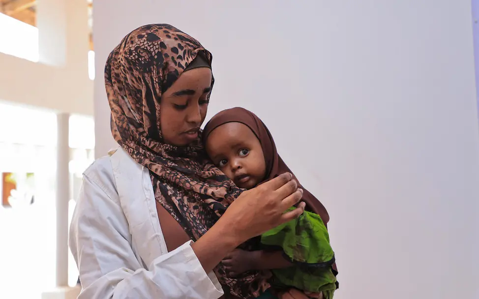 Eine Krankenschwester mit Kind | © UNICEF/UNI890565/Yasin Eine Krankenschwester mit Kind auf dem Arm