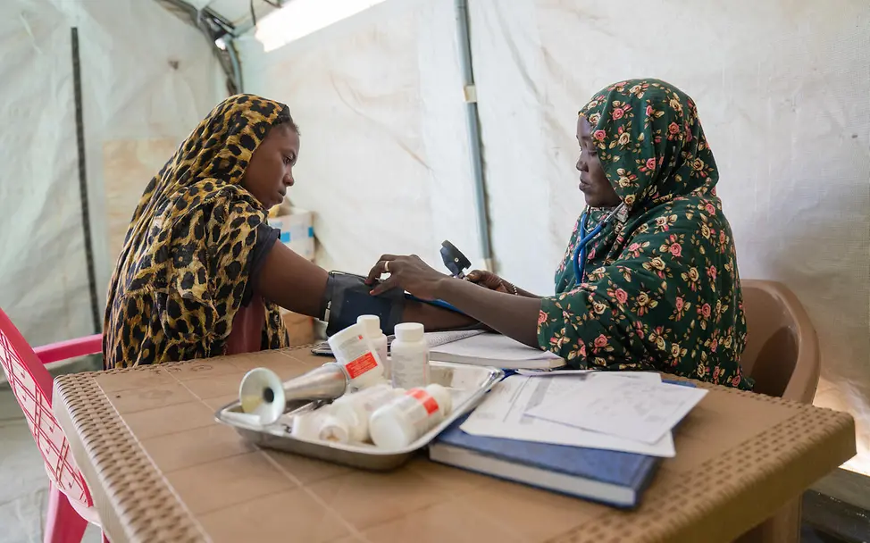 Hebamme und Schwangere bei Untersuchung | © UNICEF/UNI941774/Jamal Eine Frau nimmt den Blutdruck einer anderen Frau