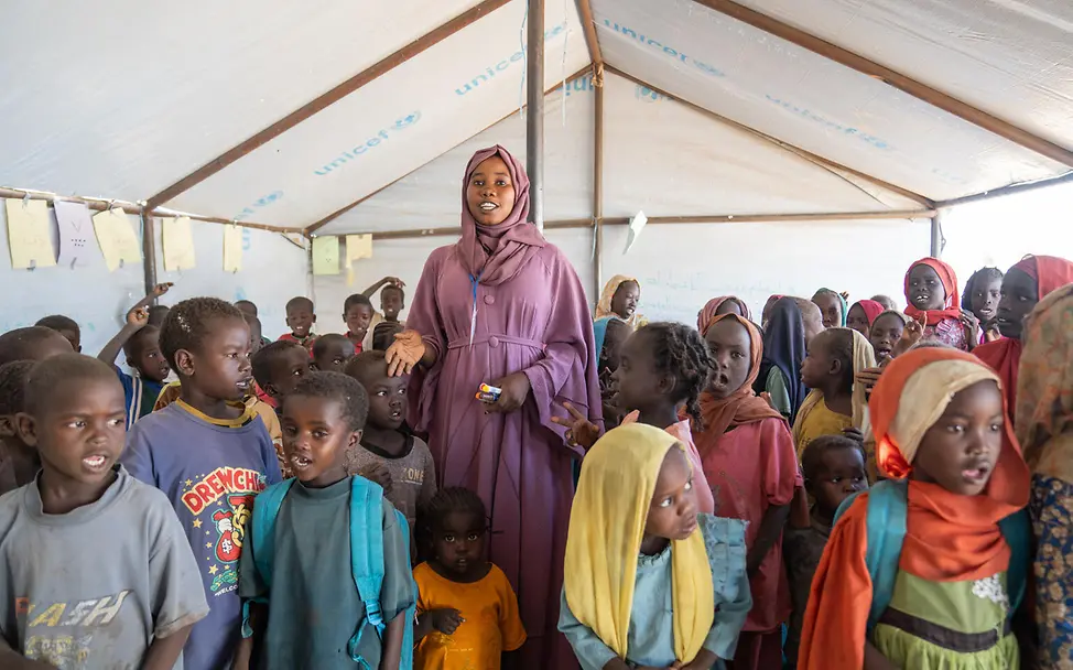 Latifa im kinderfreundlichen Zentrum | © UNICEF/UNI941832/Jamal Eine junge Frau um sie herum Kinder