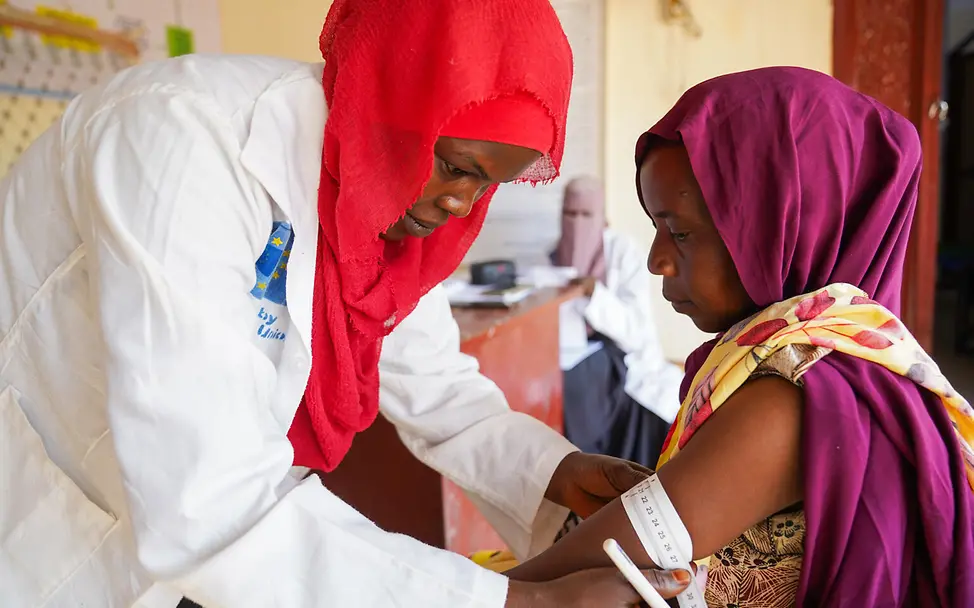 Fadeela Ahmed untersucht Kinder und Mütter auf Mangelernährung | © UNICEF/UNI939222/Jamal Frau misst Oberarmumfang einer anderen Frau