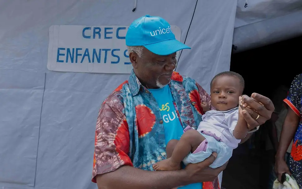 Ein UNICEF Mitarbeiter mit Baby | © UNICEF/UNI878208/Badimu Ein UNICEF Mitarbeiter mit Baby